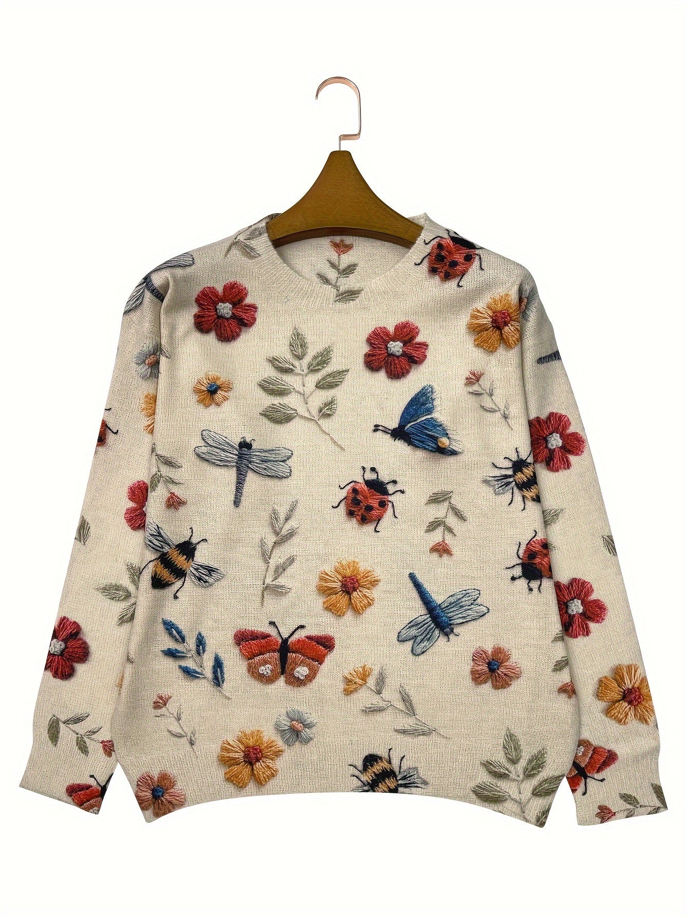Beige sweater with floral and insect patterns on a hanger against a white background