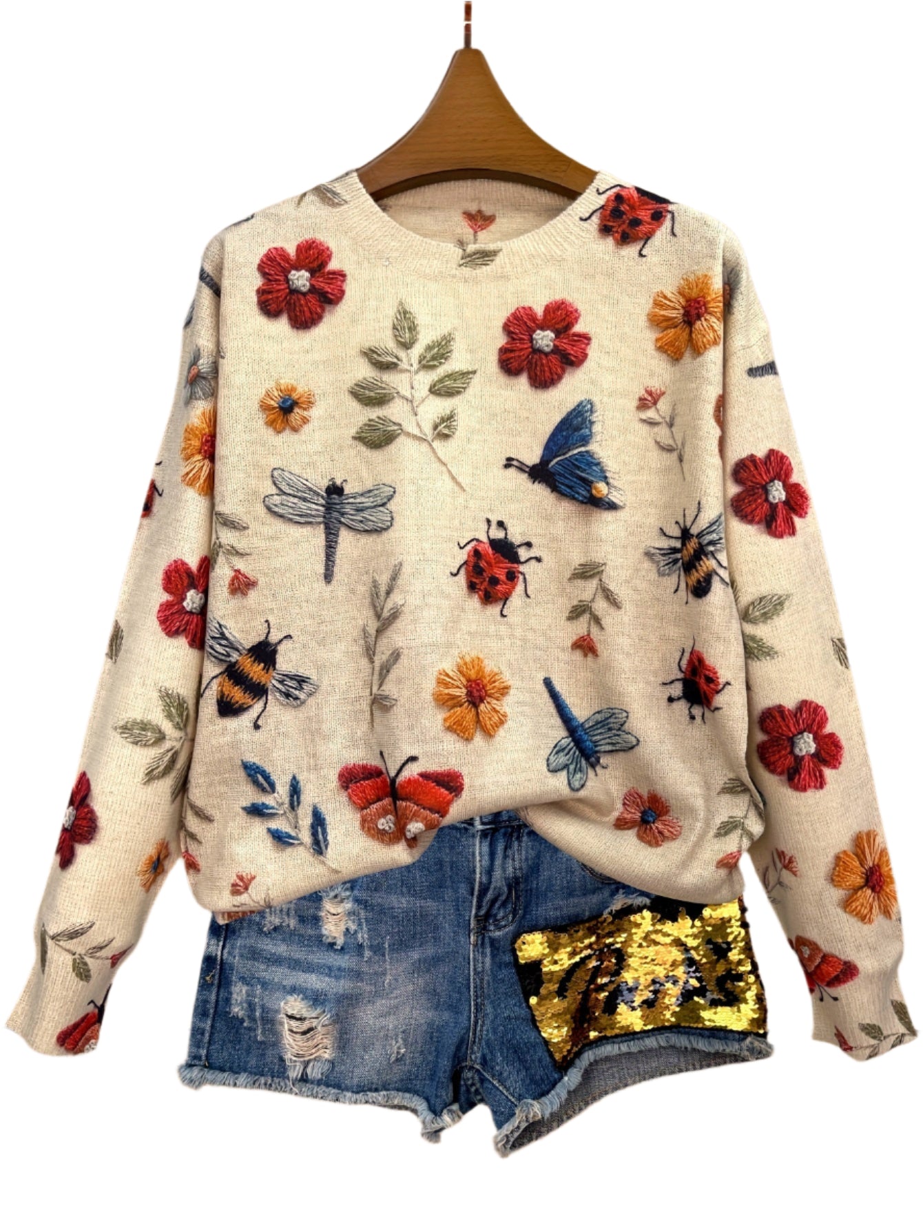 Sweater with floral and insect patterns on a wooden background