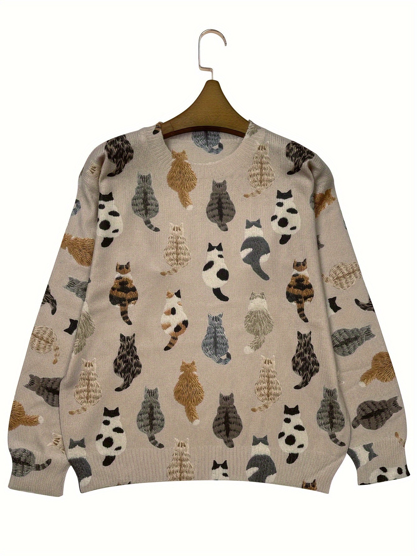 Beige sweater with cat pattern on a hanger against a white background