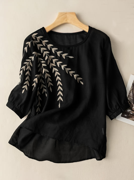 Black blouse with leaf embroidery on a beige background